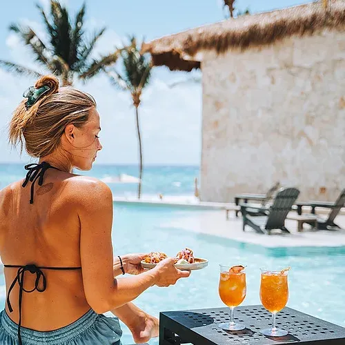 Woman enjoys food by pool at The Fives Corpo