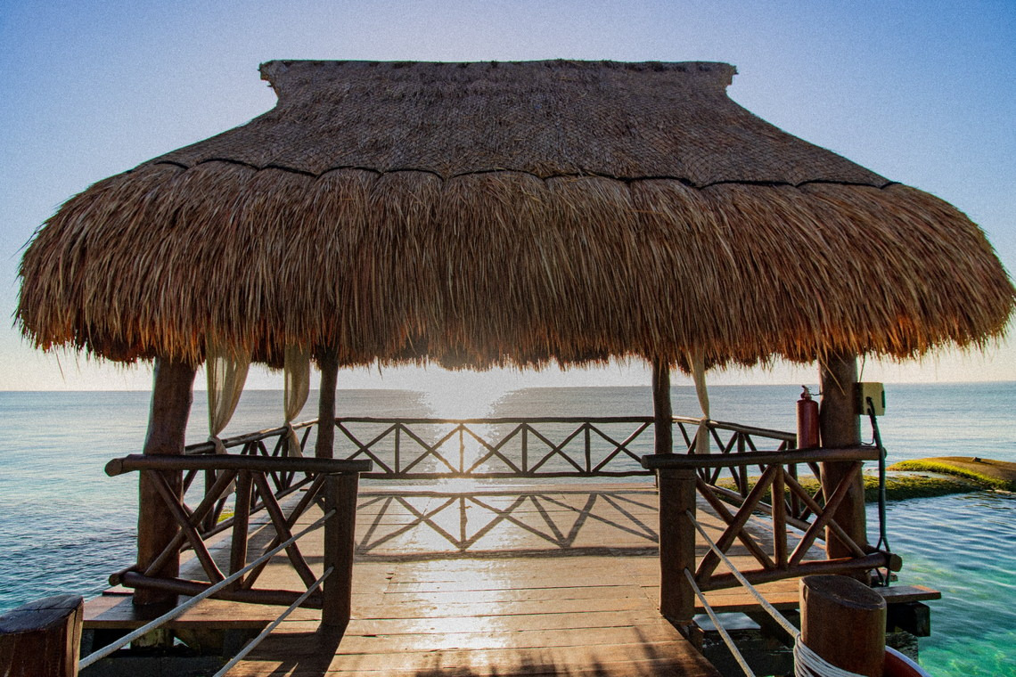 Thatched-roof gazebo over the ocean, perfect for The Fives Corpo relaxation.
