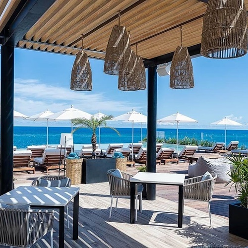 a patio with tables and chairs overlooking the ocean