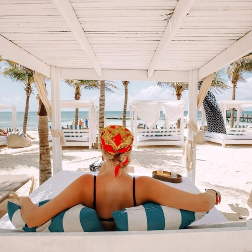 Relax at The Fives Corpo Beach Club: Caribbean beach view, Balinese beds, and palm trees.