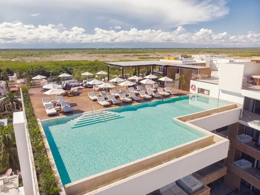 Piscina infinita en la azotea de un hotel con tumbonas y vistas al mar, perfecto para The Fives Corpo.