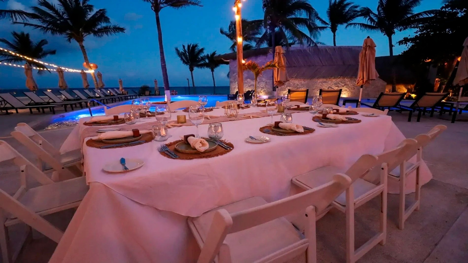 a long table with a white table cloth and white chairs