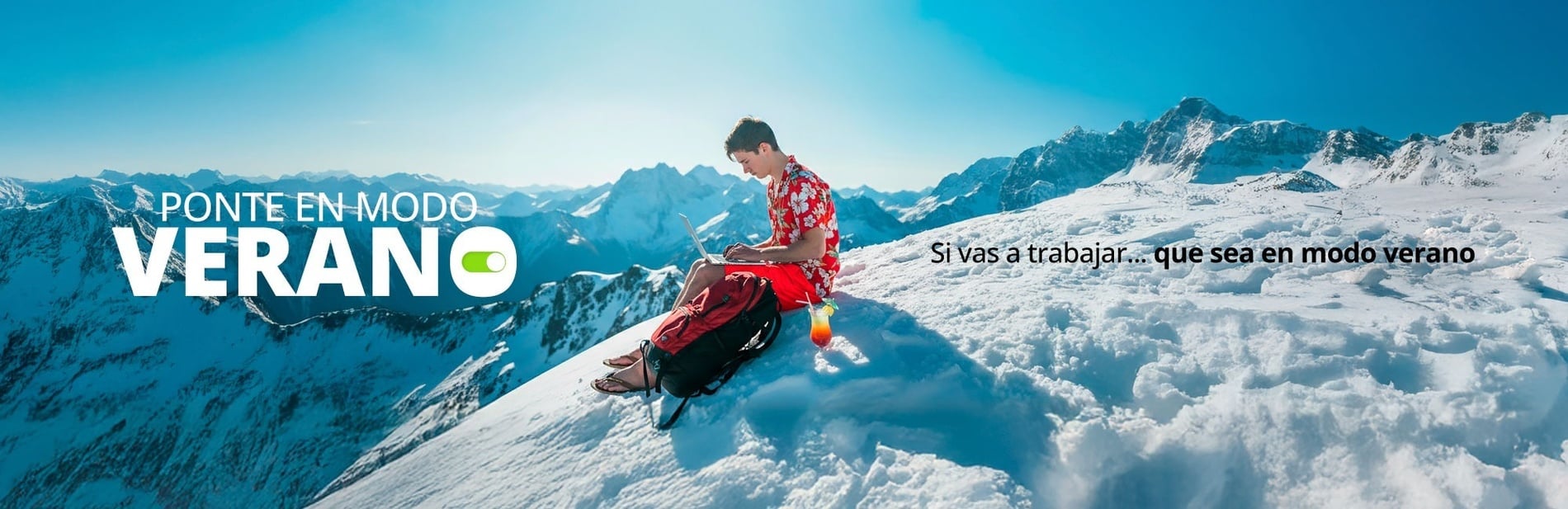 Un joven con atuendo veraniego, portátil y cóctel se sienta en una montaña nevada, encarnando irónicamente el mensaje "Ponte en modo verano" y la despreocupación de no necesitar "ni un suéter".