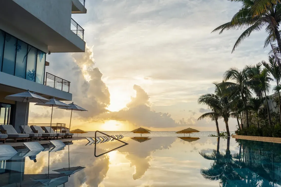 Stunning infinity pool at The Fives Hotel with palm trees at sunset.