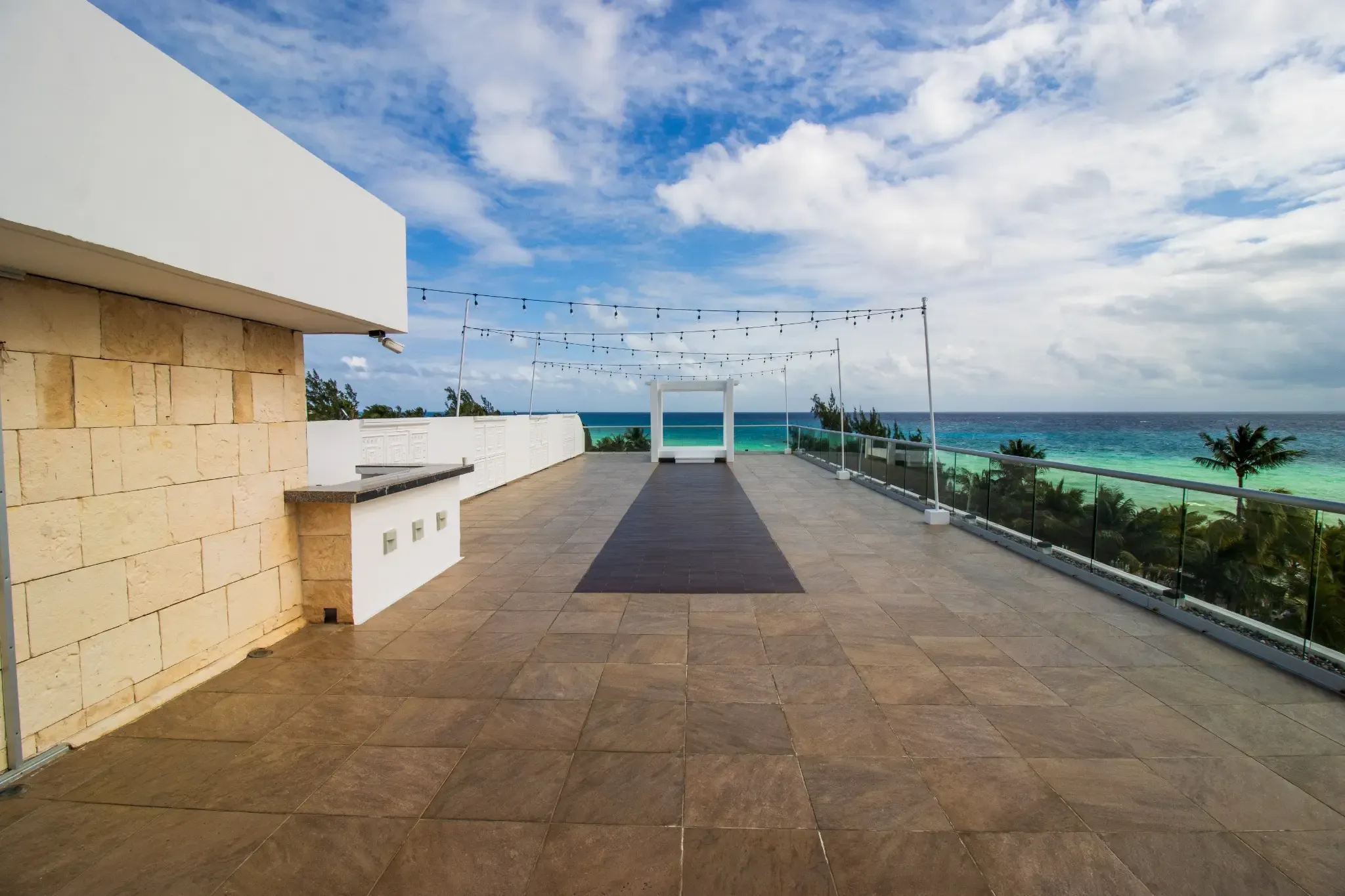 Rooftop event space with ocean view, string lights, and wedding arch. The Fives Corpo