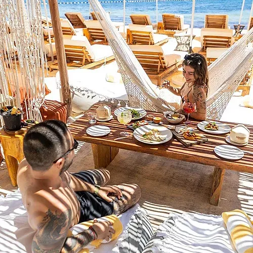Couple enjoying food at The Fives Corpo beach resort with hammock.