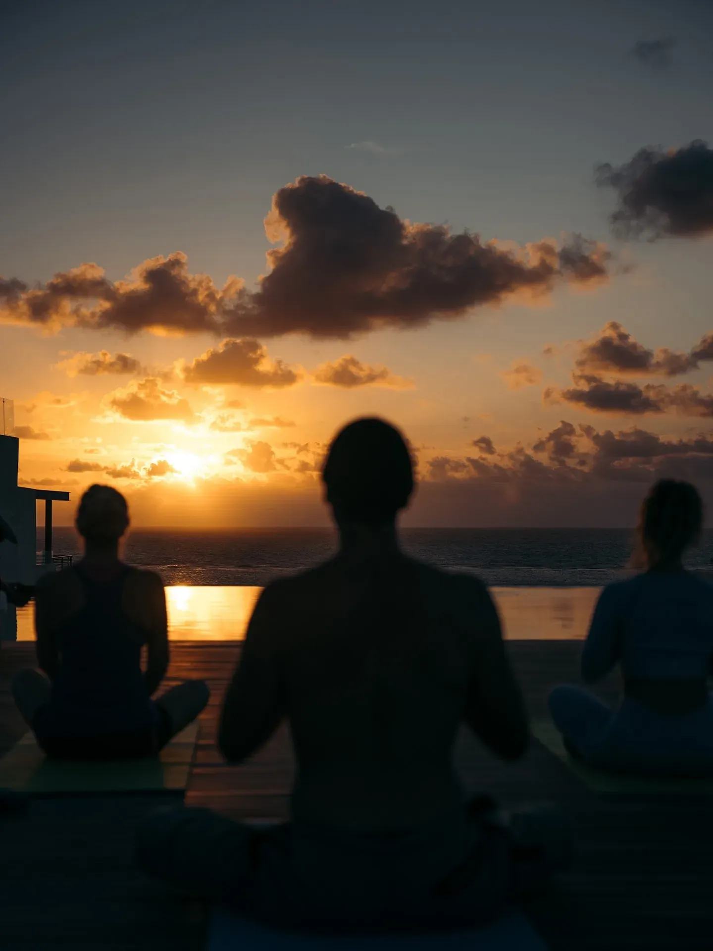Group meditating at sunset at The Fives Corpo. Oceanfront yoga session.