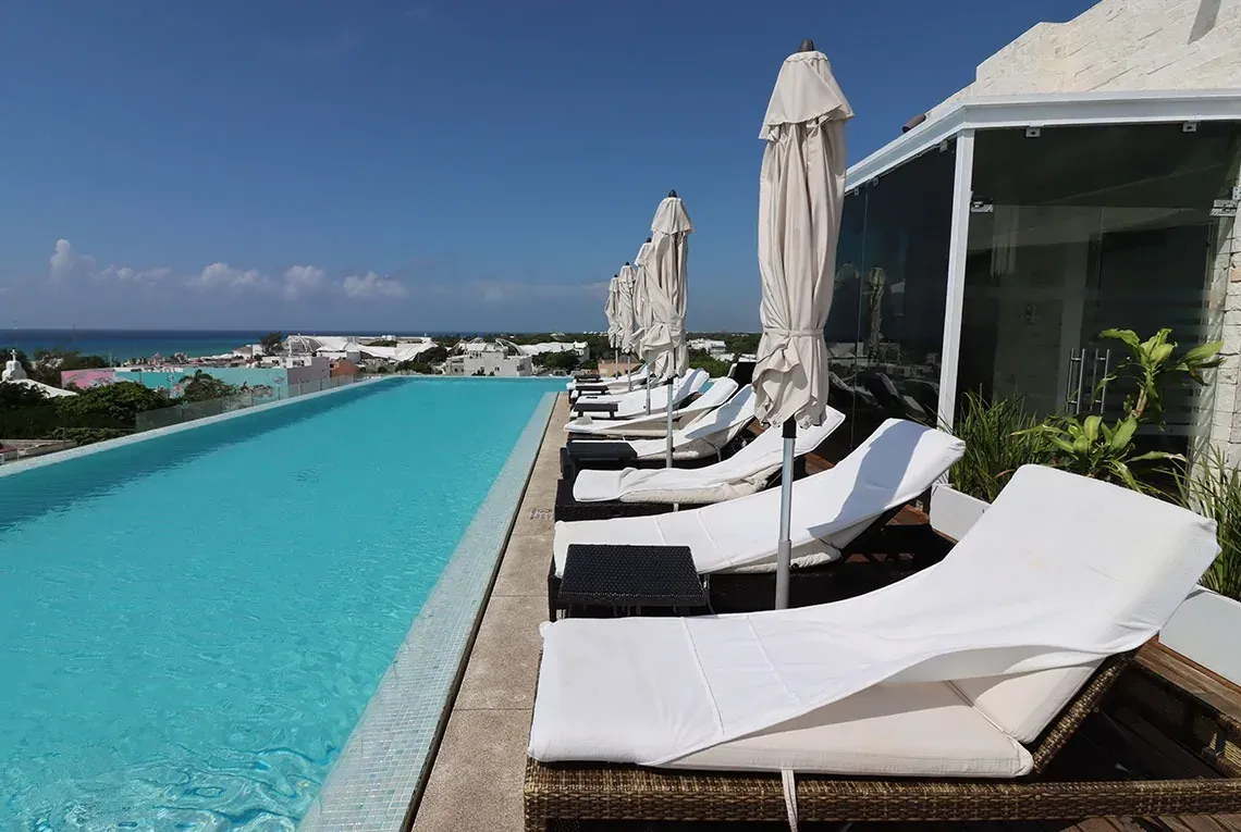 The Fives Corpo infinity pool with loungers and umbrellas, offering ocean views.