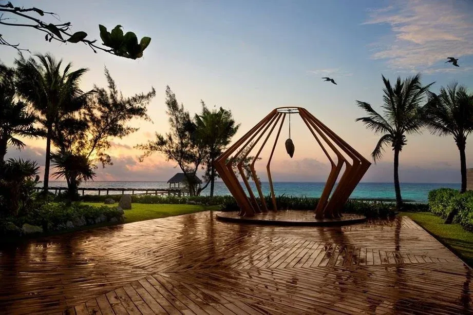 The Fives Corpo resort: Sunset over turquoise ocean with wooden deck and palm trees.