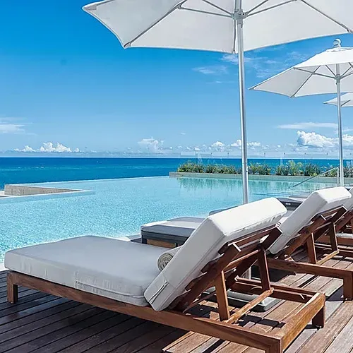 The Fives Corpo: Lounge chairs by infinity pool overlooking the blue sea.