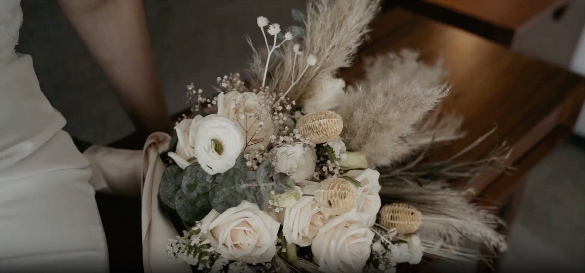 a woman in a white dress is holding a bouquet of white flowers
