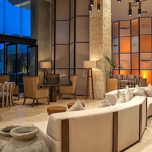 The Fives Corpo lobby: Curved sofas, rattan chairs, and floor lamps.