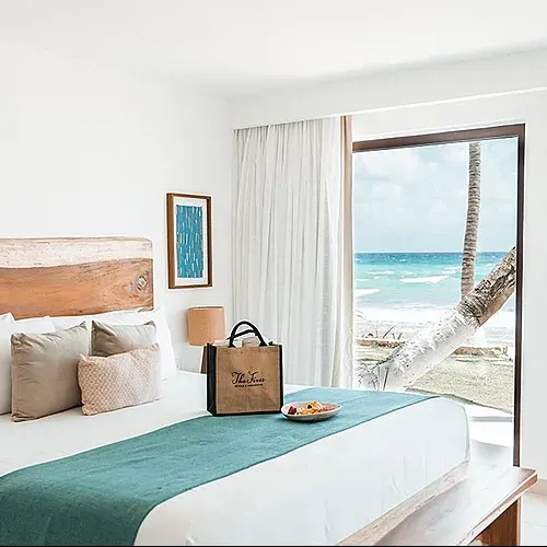 Oceanfront hotel room at The Fives Corpo with king bed, welcome bag, and Caribbean view.