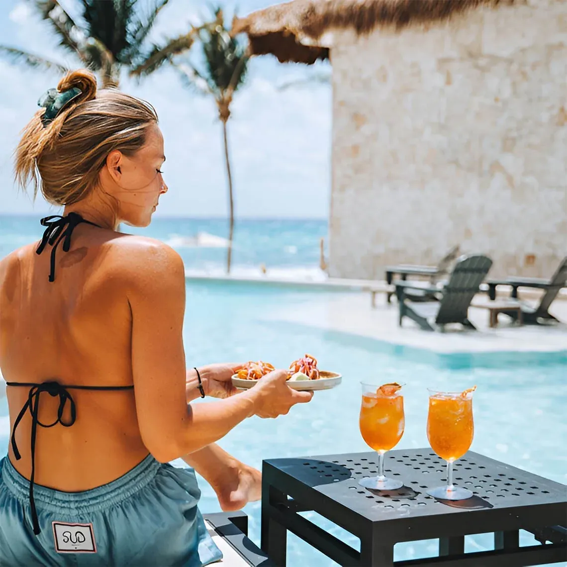 Woman enjoys poolside cocktails and food at The Fives Corpo.
