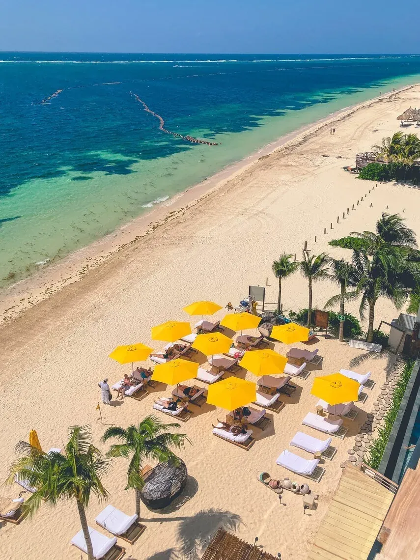 Relax under yellow umbrellas at The Fives Beachfront, with comfortable sun loungers.