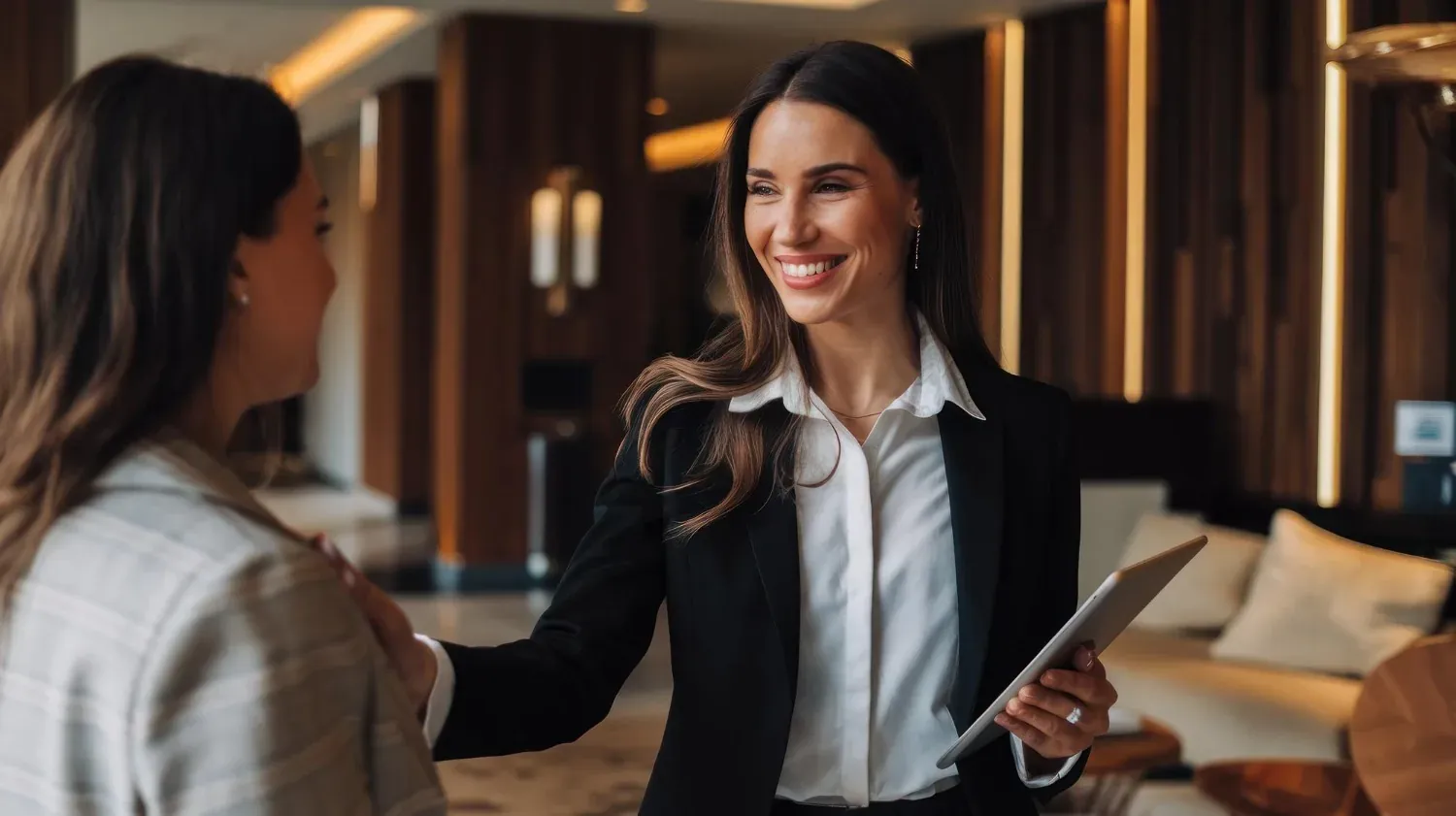 Recepcionista de The Fives Corpo sonriendo y entregando una tableta a un huésped.