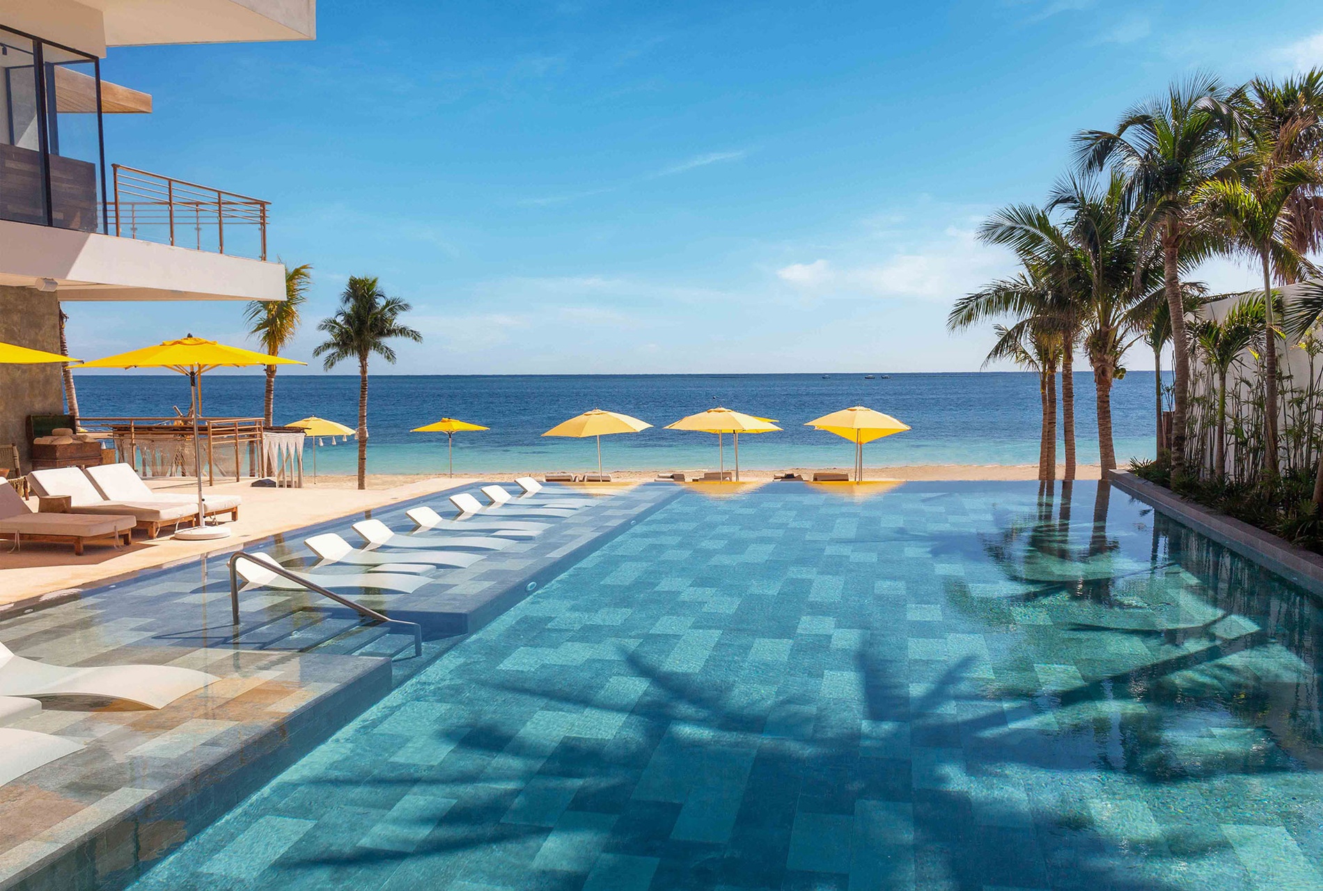 Infinity pool with ocean views and yellow umbrellas at The Fives Corpo resort.