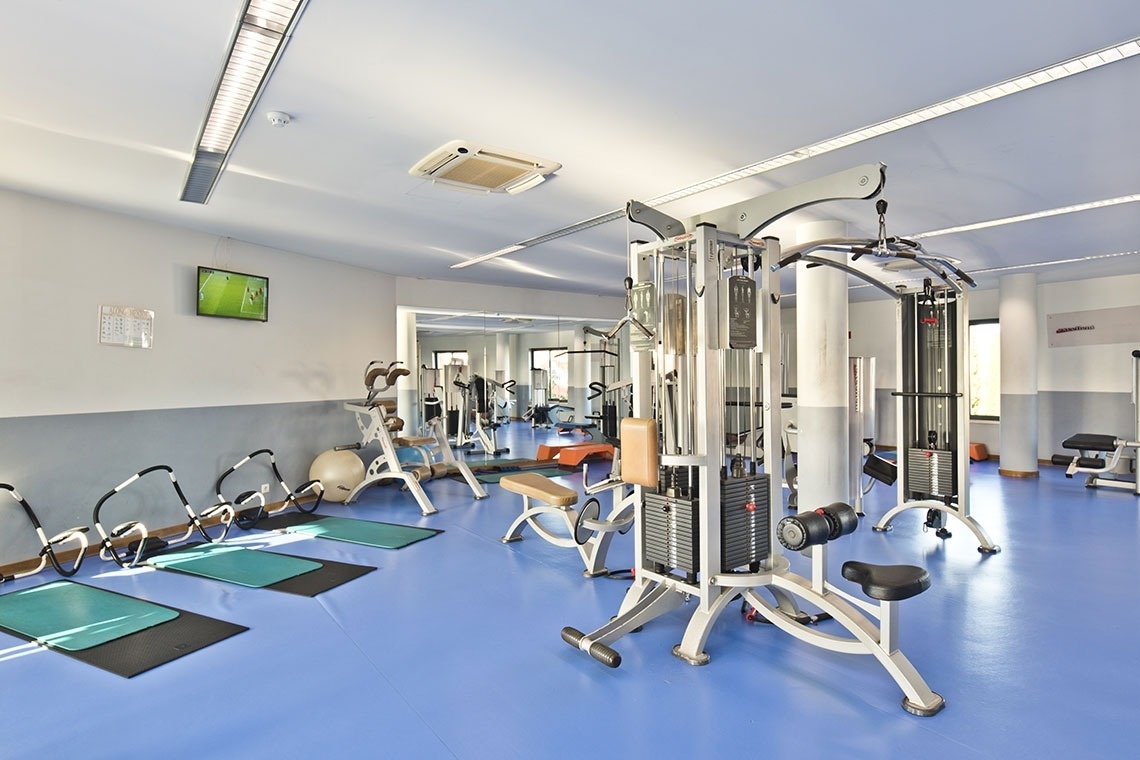 Gimnasio moderno en Lam Hotel Estarreja con máquinas de pesas y esterillas.