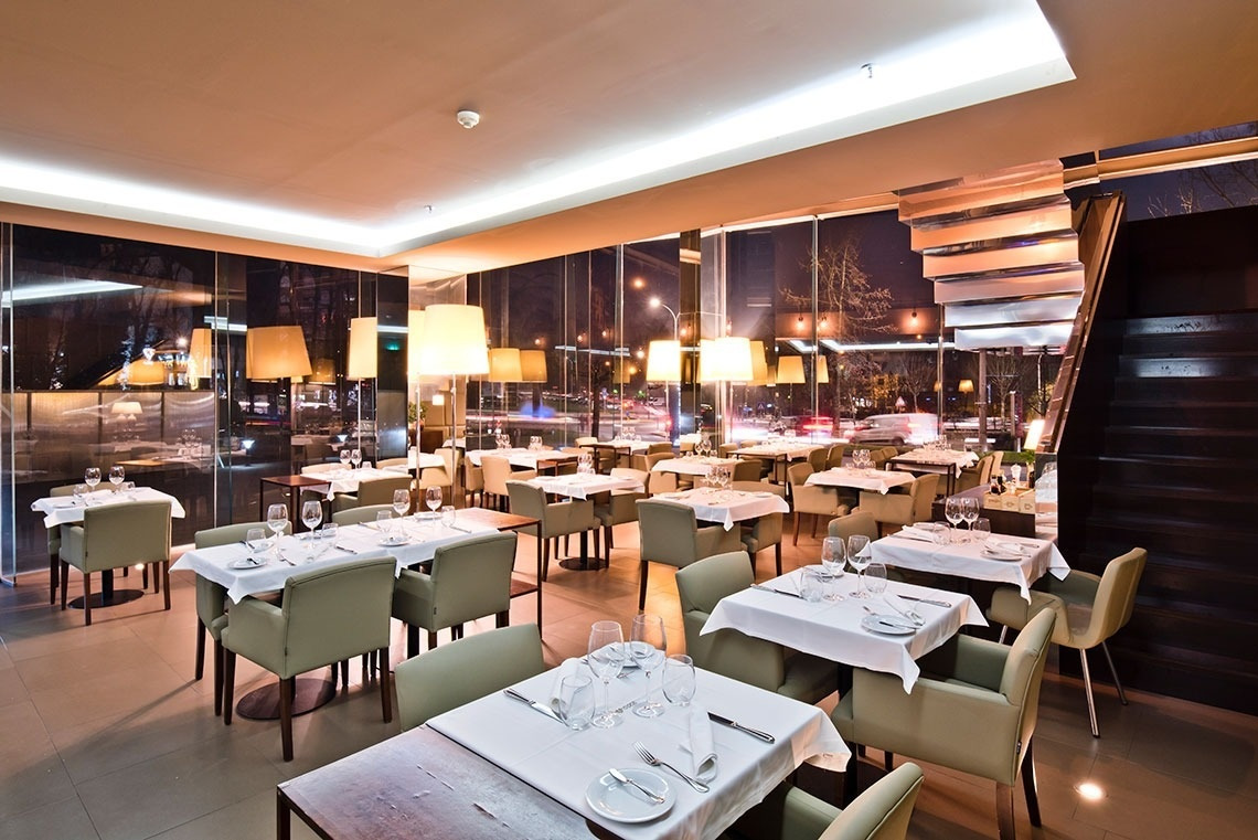 Elegant restaurant with tables set for dinner at Golden Tulip Sao Joao da Madeira | Official website.