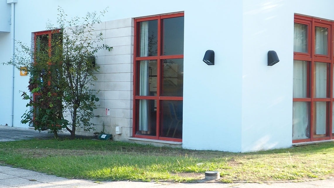 um prédio branco com janelas vermelhas e um sinal amarelo na parede