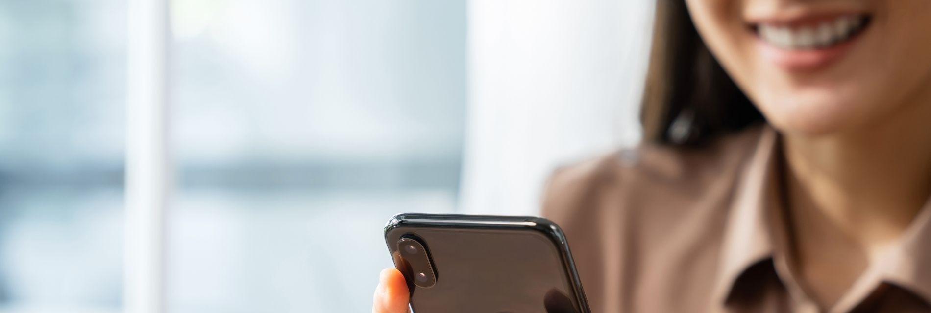 a woman is smiling while holding an iphone in her hand