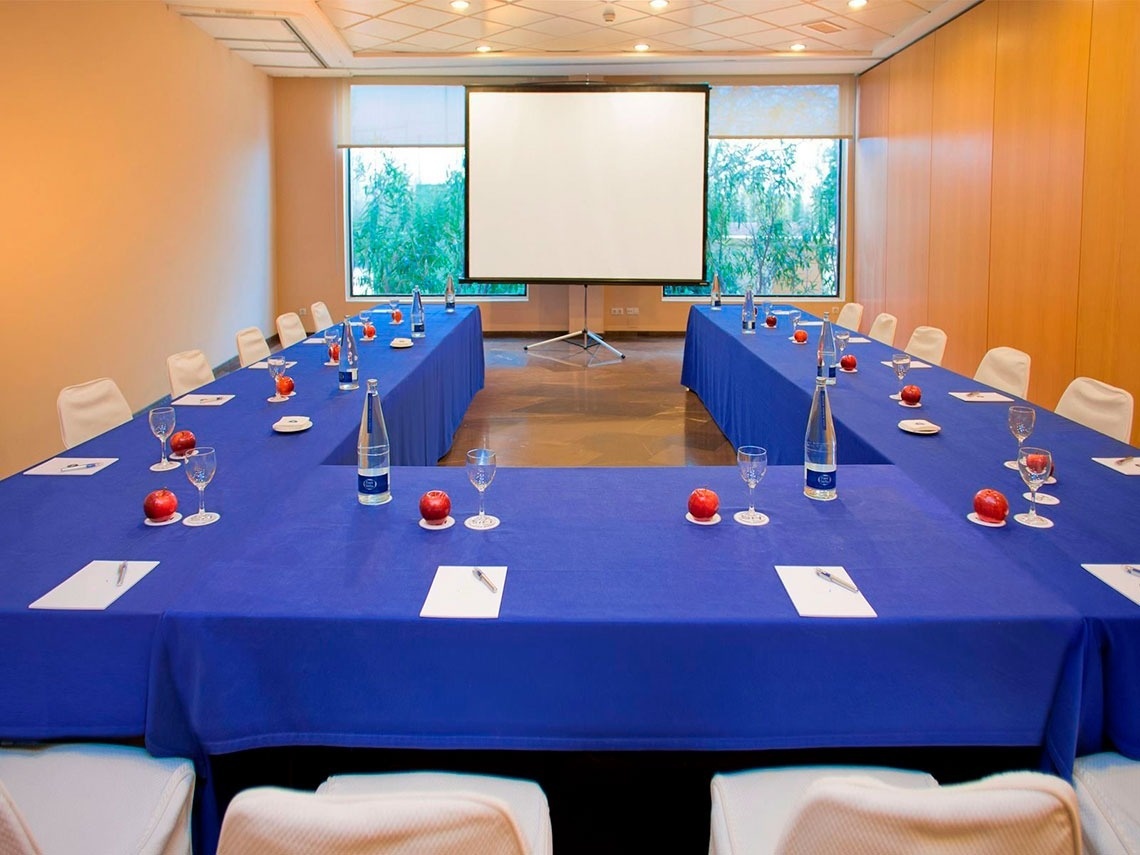 Sala de conferencias con mesa en forma de U, sillas y proyector. Ideal para eventos en Flag Hotel Valencia | Web oficial.