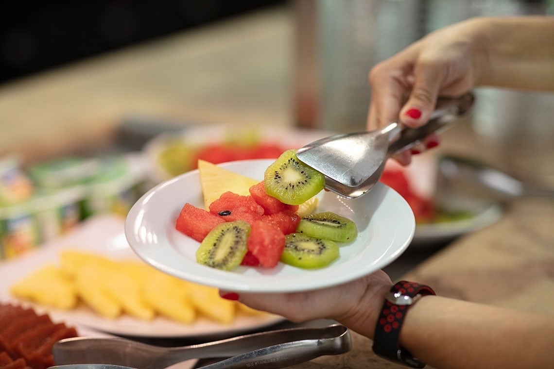Campanile Setúbal: Selecione frutas frescas, como kiwi e melancia, com pinças em um buffet.