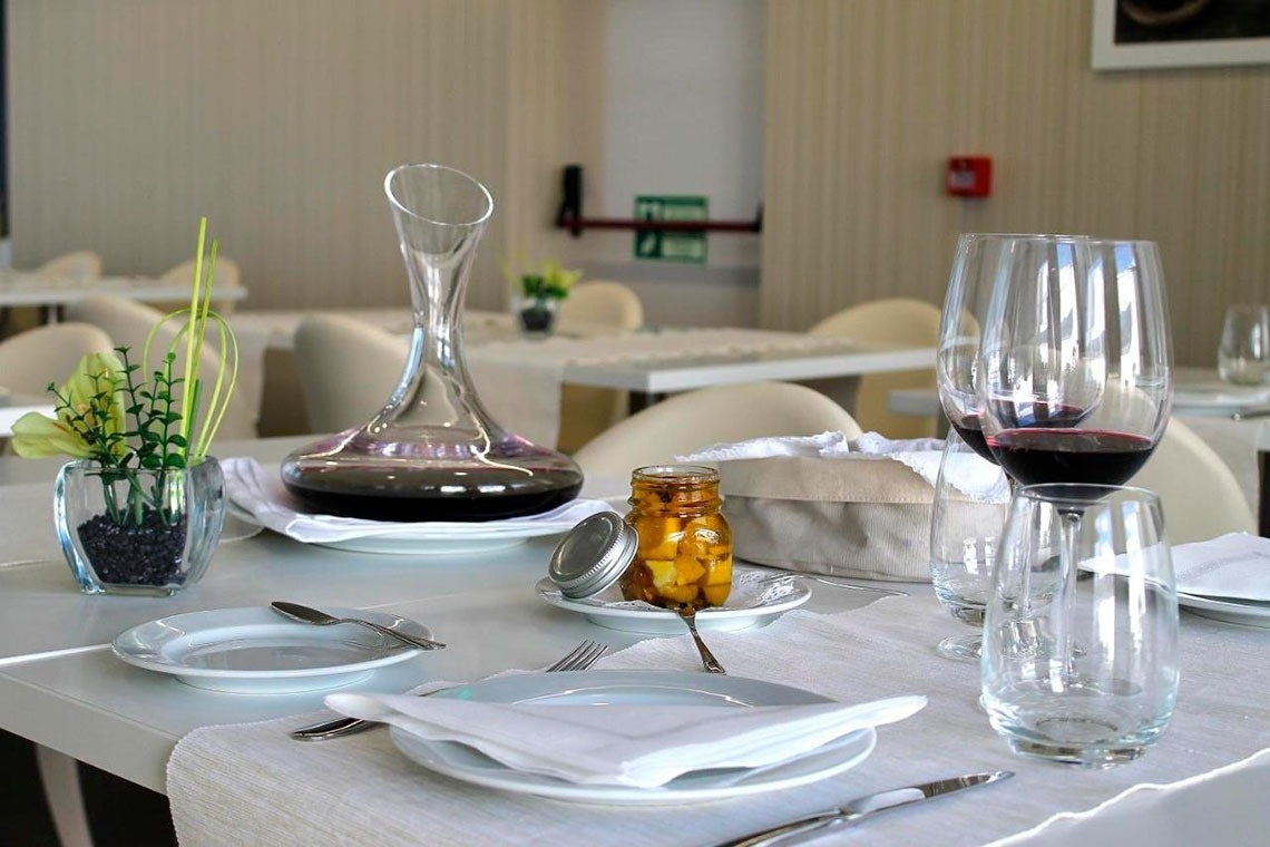 Mesa elegante em hotel com decantador de vinho e flores. Flag Hotel Aljustrel | Site oficial.