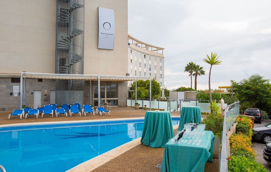 Piscina y terraza del Hotel Flag Valencia con tumbonas y mesas listas para eventos. ¡Reserva ya!
