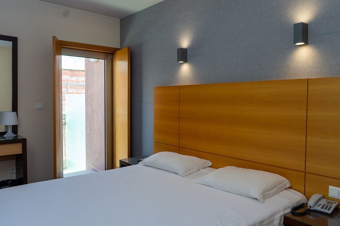 Modern hotel room at Flag Hotel Barcelos with king-size bed and balcony door.