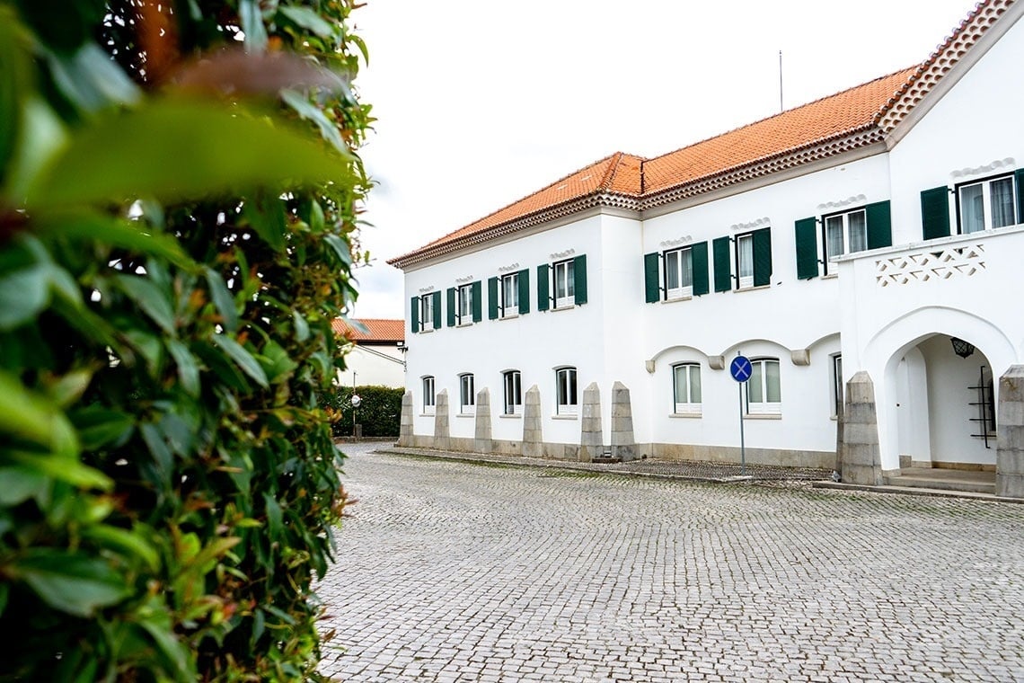 um prédio branco com janelas verdes e um sinal azul