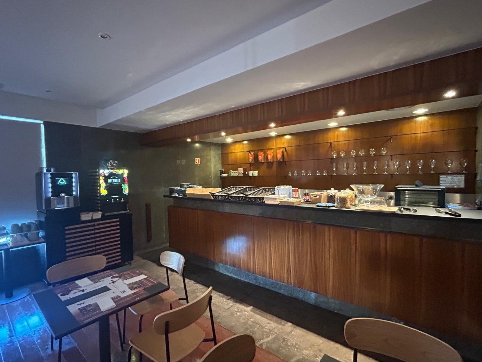 Bar de hotel con dispensador de jugos y mesas. Flag Hotel Campo Maior | Sitio Oficial.