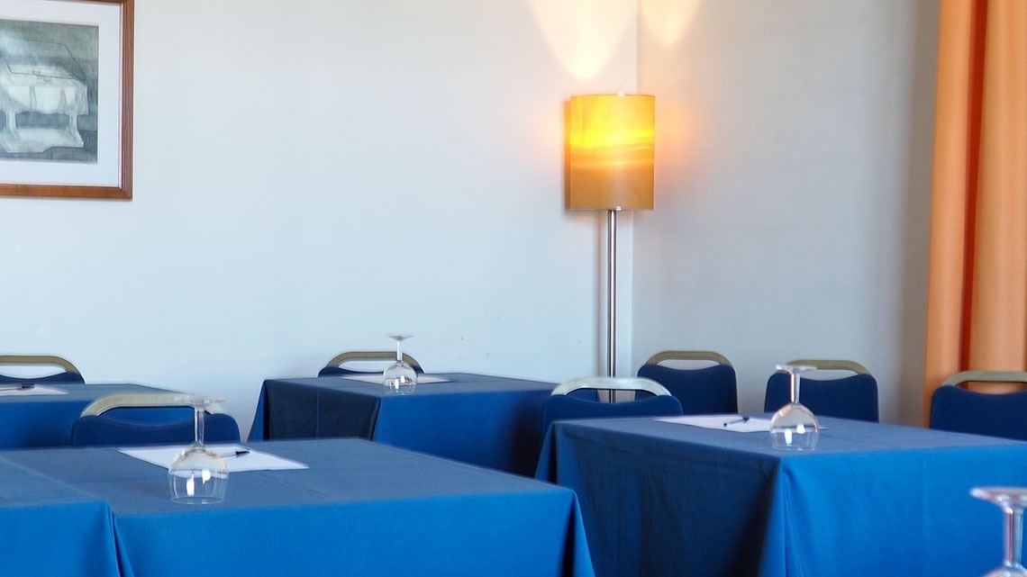 Salas de reunião do Hotel Porto-Maia: mesas azuis, cadeiras e iluminação ambiente.
