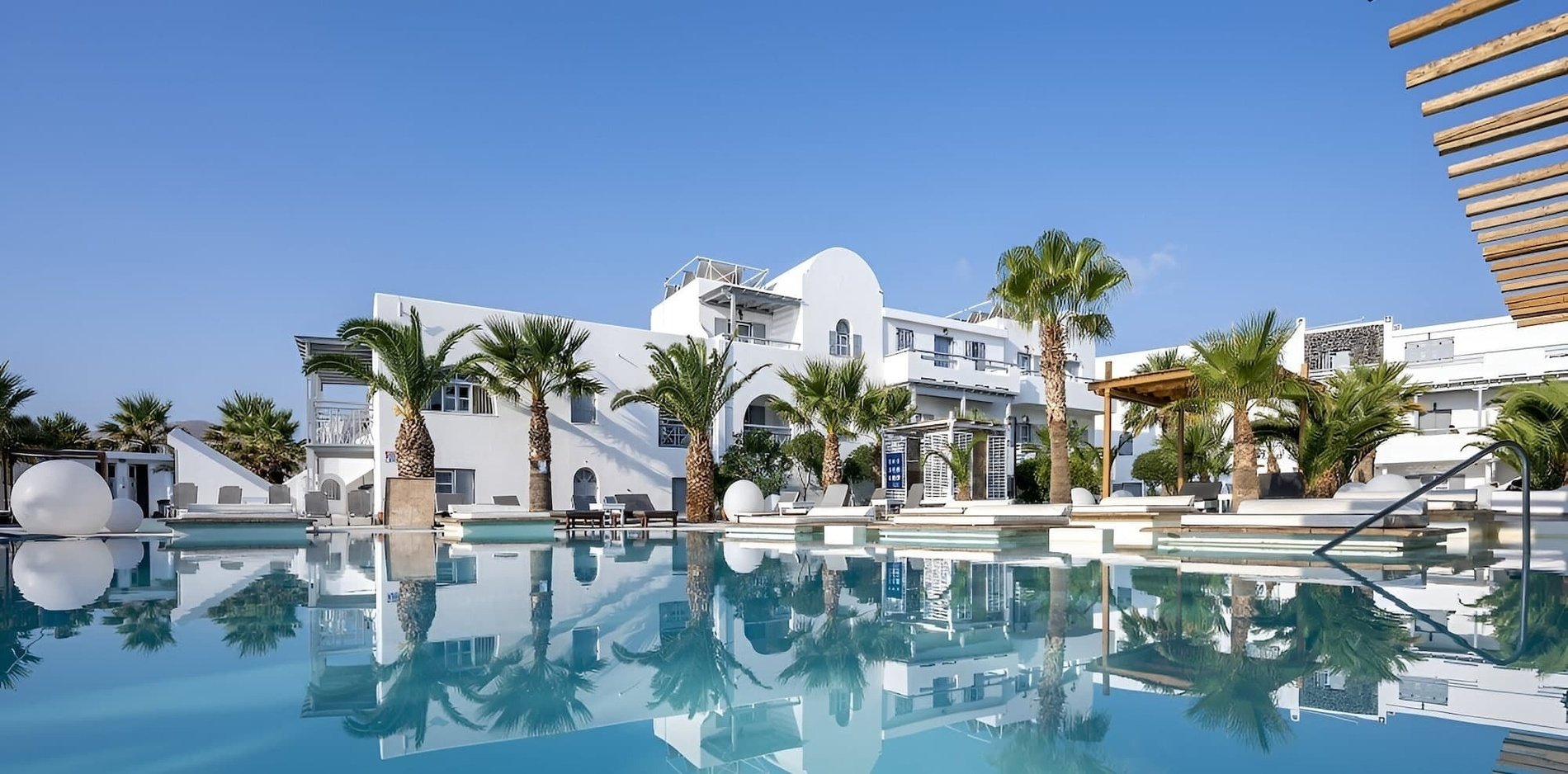 una piscina con palmeras y un edificio blanco en el fondo