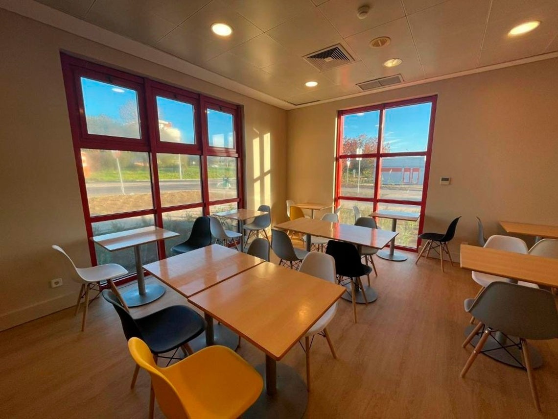 Refeições e descanso no Flag Hotel Porto-Maia: mesas e cadeiras modernas com vista para o exterior.