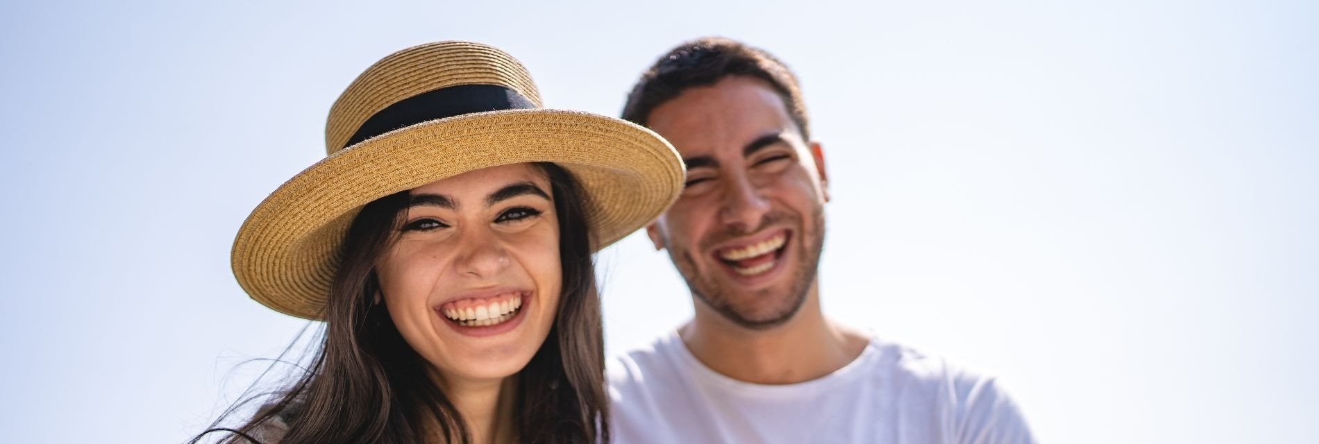 a man and a woman are laughing together and the woman is wearing a straw hat