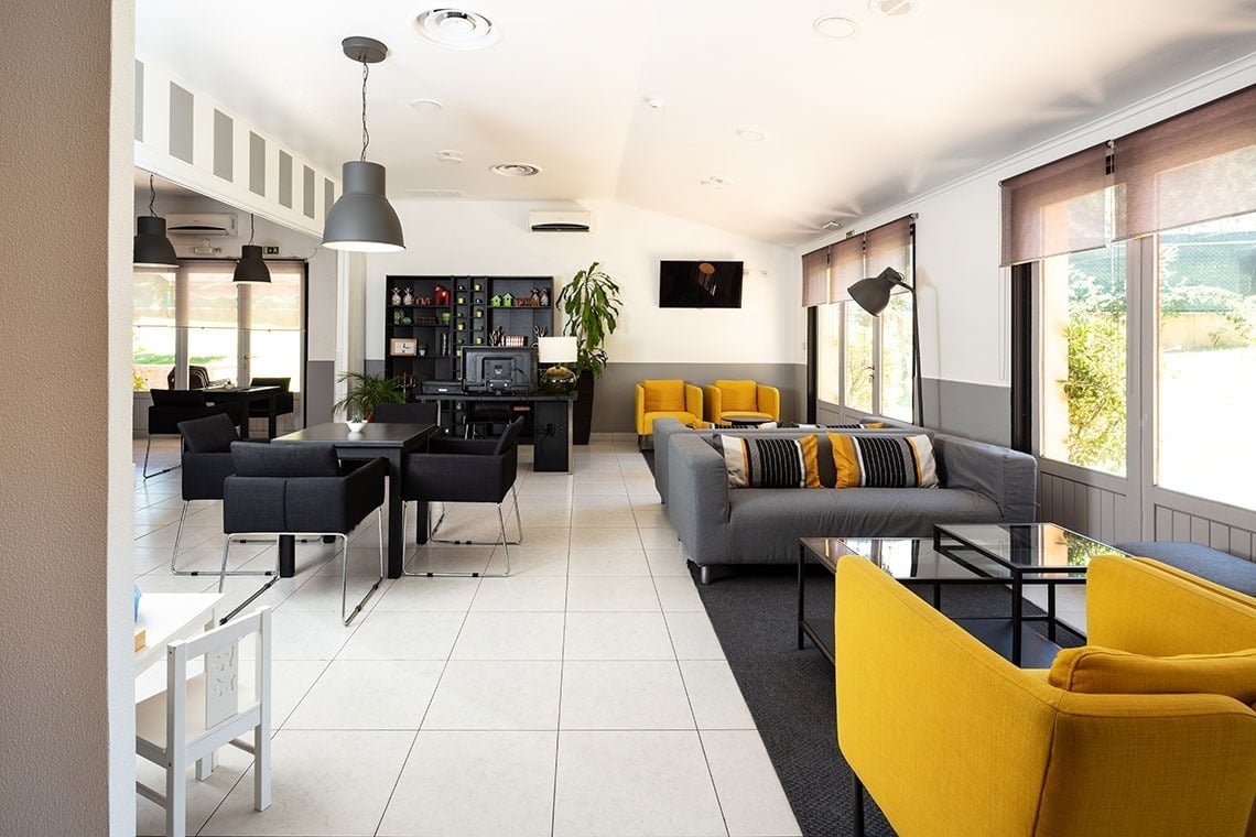 Sala de estar moderna no Campanile Setúbal | Website oficial, com sofás amarelos e cinzentos.