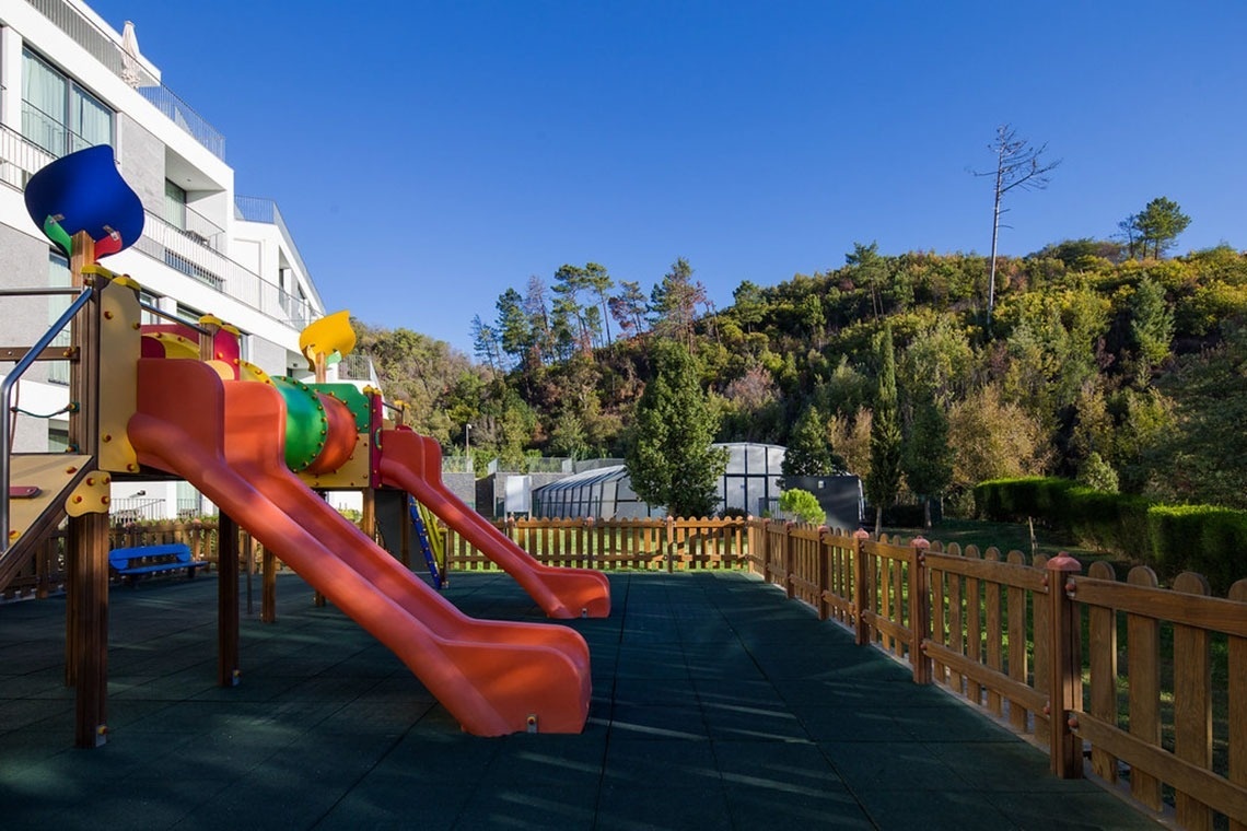 Parque infantil no Monchique Resort & SPA by Flagworld Hotels, com escorregas coloridos e vista para a natureza.