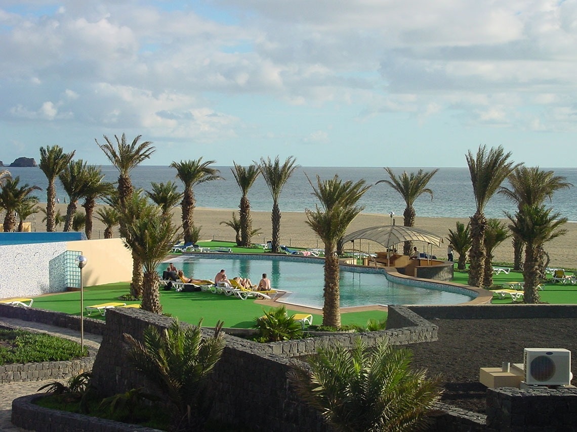 a large swimming pool surrounded by palm trees on a beach