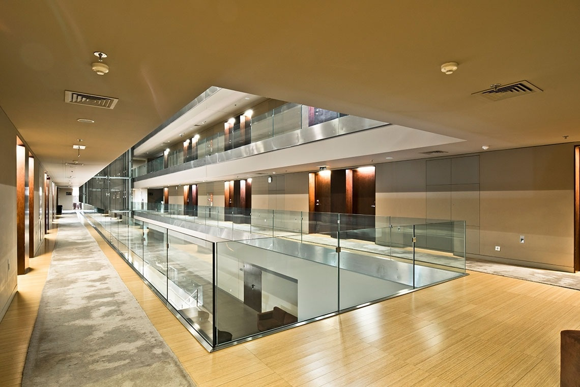 Modern hotel interior at Golden Tulip Sao Joao da Madeira, featuring glass railings and warm lighting.