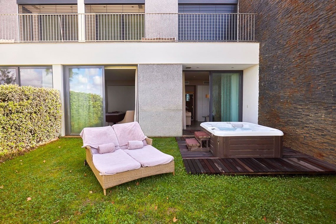 Jacuzzi exterior com espreguiçadeiras e vista para o jardim no Monchique Resort & SPA by Flagworld Hotels.