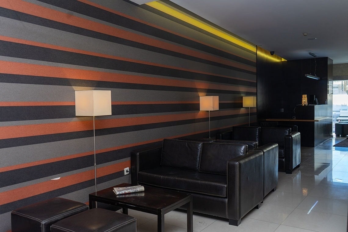 Modern lobby with striped walls and leather seating. Flag Hotel Barcelos | Official website