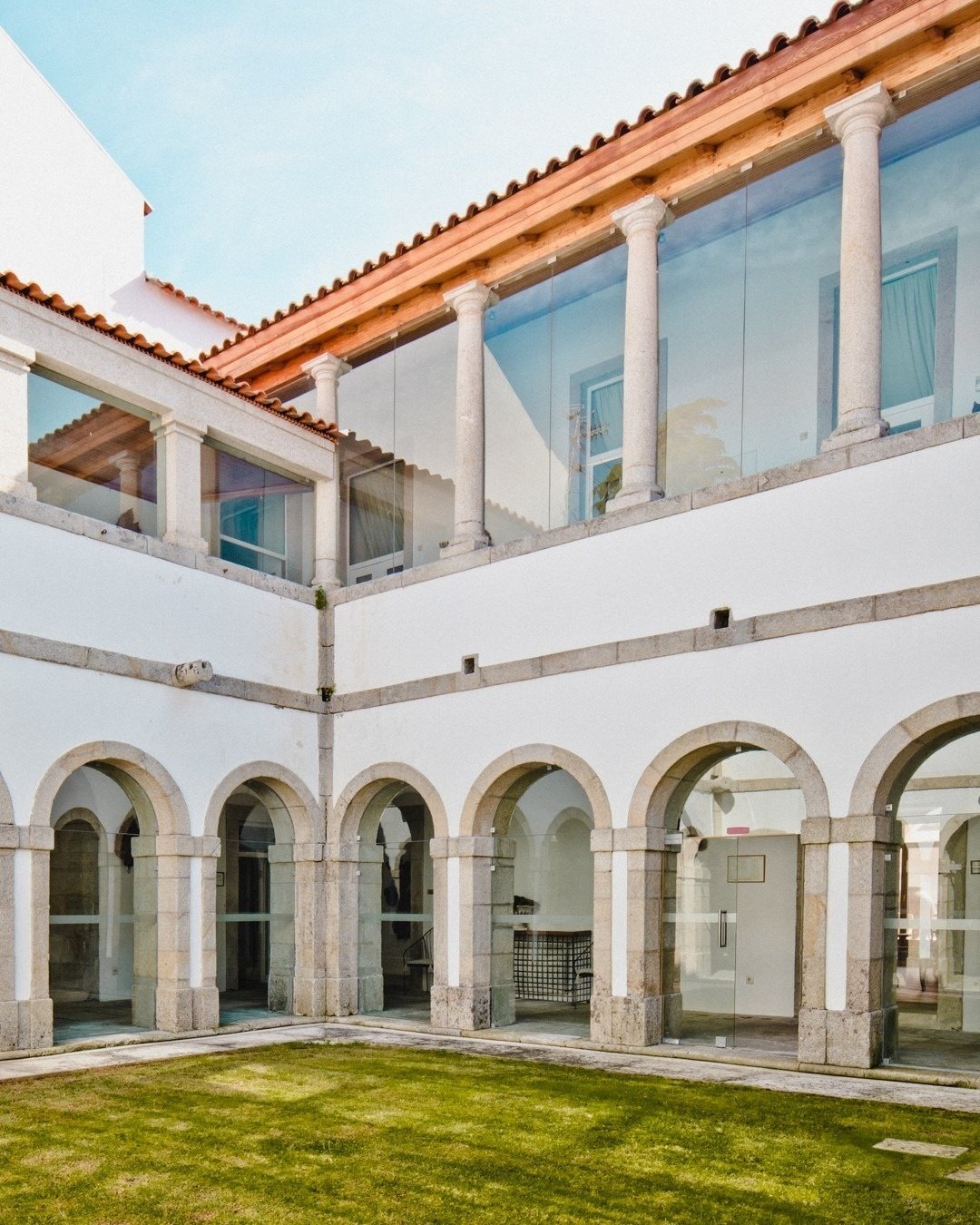 a white building with arches and columns has a glass roof