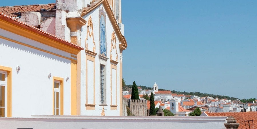 um castelo amarelo e vermelho em uma colina com a cidade ao fundo