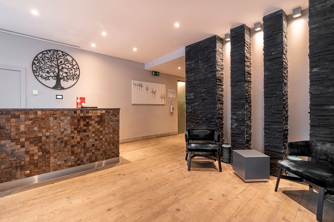 Recepção moderna do Monchique Resort & SPA by Flagworld Hotels, com detalhes em madeira e pedra escura.