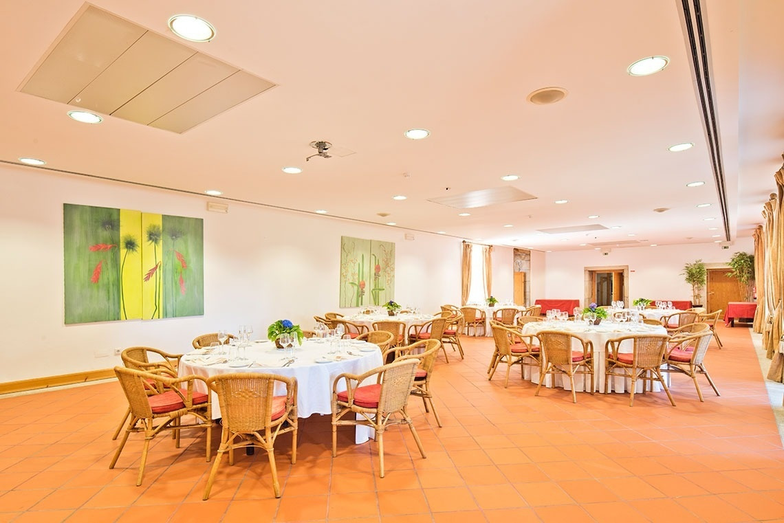 Salón del Lam Hotel Convento do Desagravo listo para eventos, con mesas redondas y sillas de mimbre.