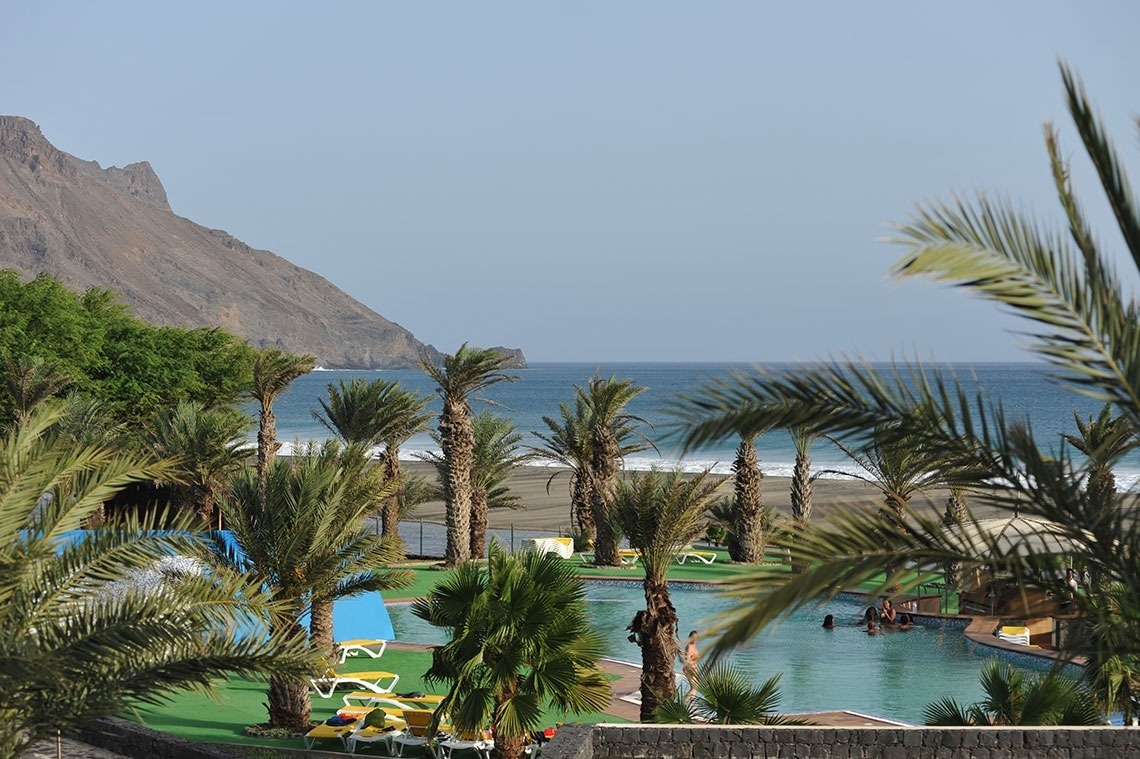 Lam Hotel Foya Branca: piscina e praia com palmeiras, vistas para montanhas e mar.