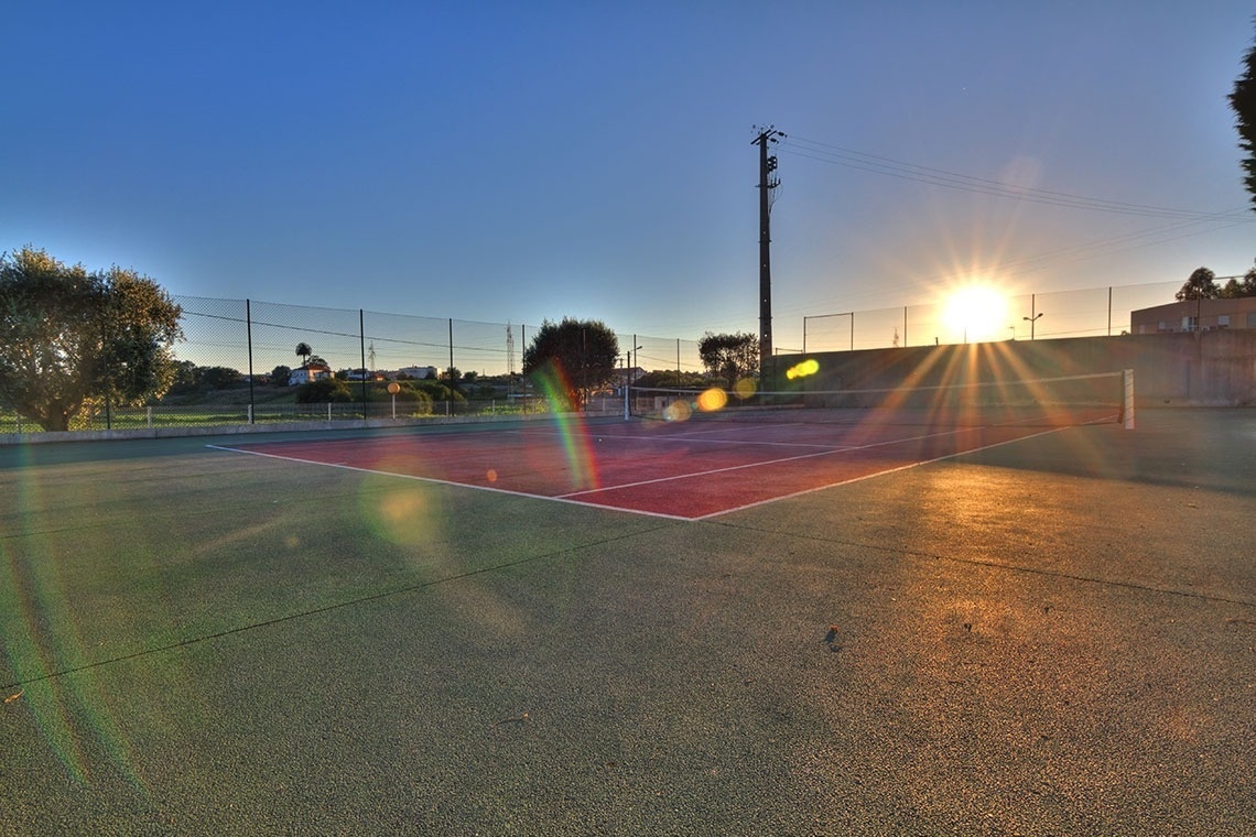 Cancha de tenis exterior en Lam Hotel Estarreja, perfecta para ejercicio al atardecer.