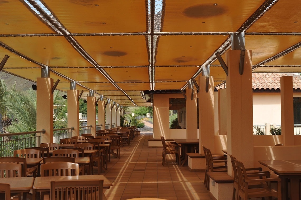 Lam Hotel Foya Branca: área externa com mesas e cadeiras sob toldo amarelo.