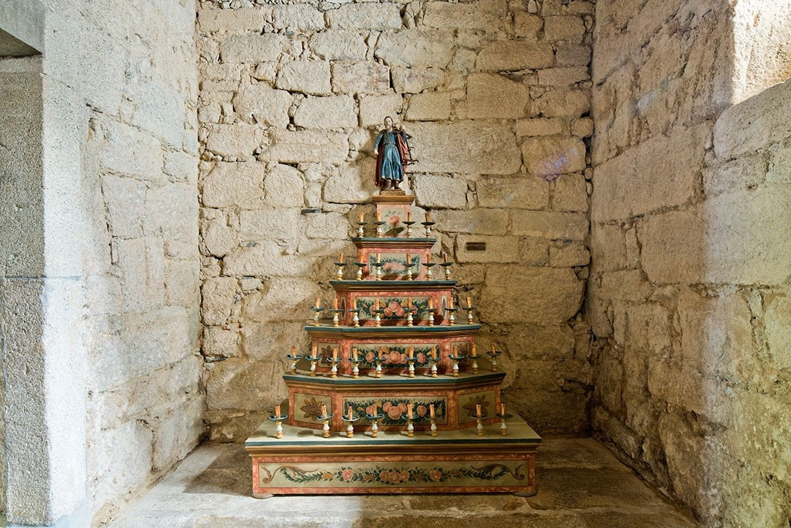 Retablo con figura religiosa y velas en el Lam Hotel Convento do Desagravo.